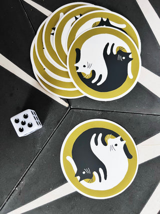 yin yang cat stickers with a die on a black tiled floor